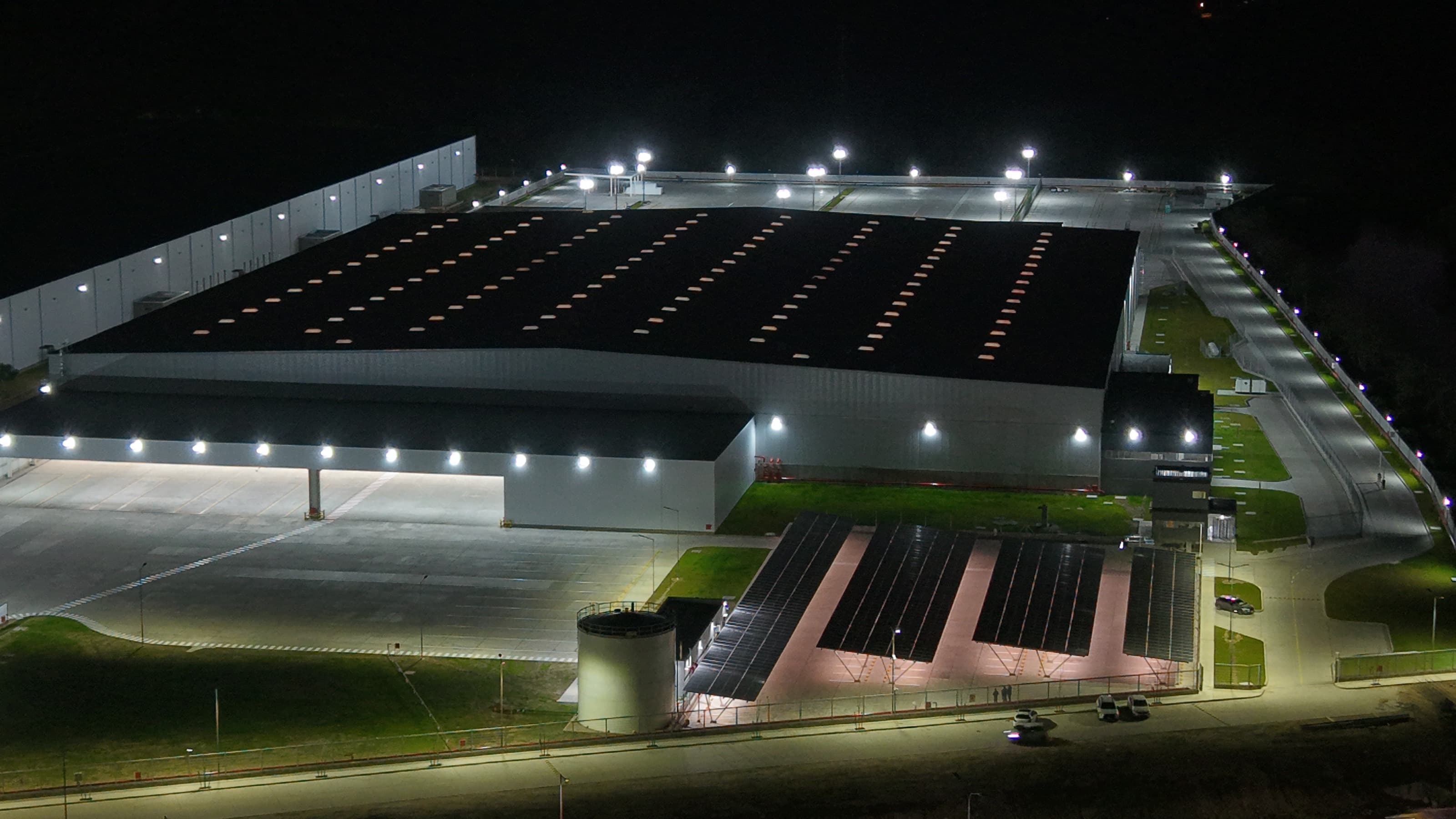Centro de distribución iluminado de noche con el carport solar